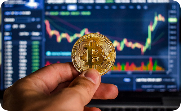 Main tenant bitcoin devant graphique boursier